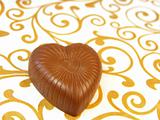 Mouthwatering chocolates in a heart-shaped on a colored background 
