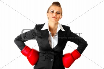 Confident modern business woman holding hands with boxing gloves on hips
