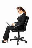 Pensive modern business woman sitting on chair and using laptop
