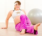 Smiling beautiful pregnant woman making gymnastics at home
