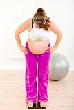 Pregnant woman standing on weight scale at home

