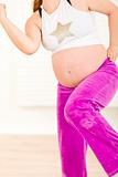 Pregnant female doing fitness exercises at home. Close-up.
