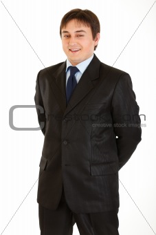 Smiling young businessman with hands behind his back
