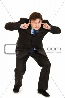 Young businessman ducking in fear and closing ears with fingers
