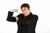 Confident young  businessman showing his  muscles
