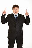 Smiling young  businessman pointing up
