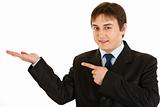 Smiling young businessman pointing finger on empty hand
