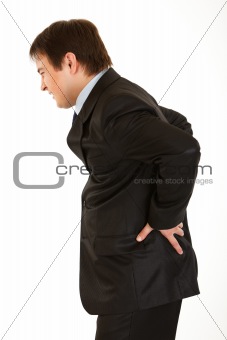 Young businessman holding his hand at his aching back
