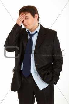 Young businessman with headache holding hand at head
