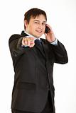 Smiling young businessman talking on mobile phone and pointing finger at you
