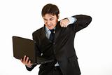 Angry young businessman trying to hit laptop
