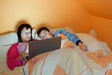 Portrait of a mother and her son using laptop while lying on the bed at home 