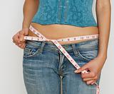 woman in jeans measuring waist