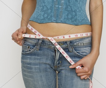 woman in jeans measuring waist