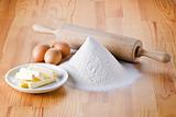 Flour with eggs, rolling pin and butter
