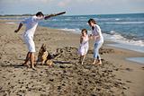happy family playing with dog on beach