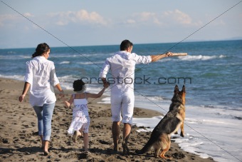 happy family playing with dog on beach