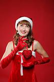 Young charming girl dressed as Santa holds a gift in the form of heart in his hands.