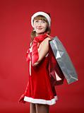 Portrait of a young charming girl dressed as Santa with a bag of shopping in their hands