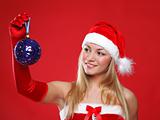 A young girl dressed as Santa Claus on a red background holds a New Year's toy