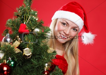 The young beautiful girl dressed as Santa and a christmas fur-tree