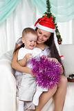 Mum and son near a christmas fur-tree opens the gift