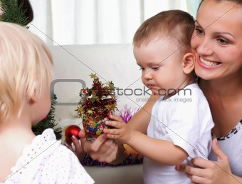 Mum and kids sits near a christmas fur-tree