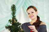 The young beautiful woman decorate a christmas fur-tree 