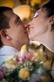 Beautiful young bride kissing groom in indoor setting