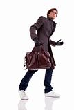 Portrait of a young man with a handbag, hasty, in autumn/winter clothes, isolated on white. Studio shot