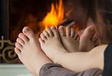 Children's feet are heated by an open fire in the fireplace