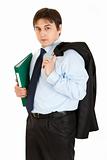 Thoughtful young businessman with jacket on his shoulder holding folder in  hand
