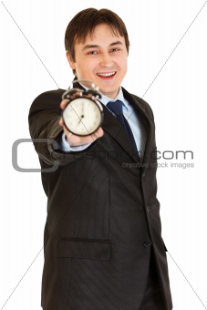 Smiling young businessman holding alarm clock in hand
