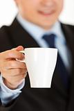 Smiling businessman offering cup of coffee. Close-up.
