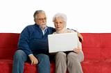 elderly couple on the sofa using a laptop