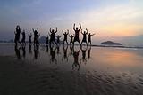 group of happy young people silhouettes jumping on the beach on 