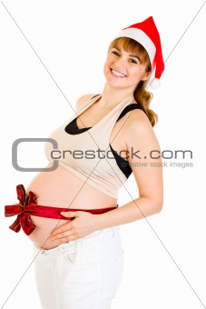 Happy beautiful pregnant woman in Santa hat with  red ribbon on belly
