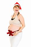 Happy christmas pregnant woman in Santa hat with  red ribbon on belly
