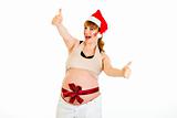 Happy christmas pregnant woman in Santa hat showing  thumb up gesture 
