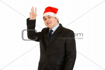 Friendly young businessman in hat of Santa Claus. Happy New Year and Merry Christmas!
