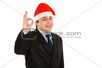 Happy young businessman in Christmas hat showing ok gesture.
