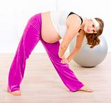 Smiling beautiful pregnant woman doing exercise at living room
