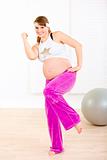 Smiling beautiful pregnant woman doing fitness exercises at home
