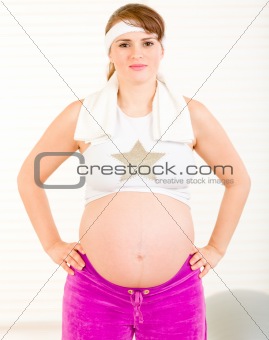 Smiling beautiful pregnant woman in sportswear and towel around her neck
