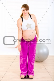 Dissatisfied with her weight pregnant female standing on weight scale
