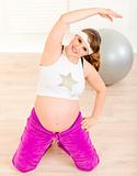 Smiling beautiful pregnant woman doing fitness exercises at home
