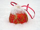 Red Christmas ball lies in the snow 