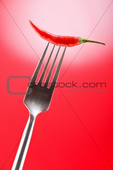 Hot pepper on the fork against colour background