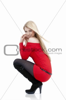 young woman with blond hair in red dress sitting - isolated on white