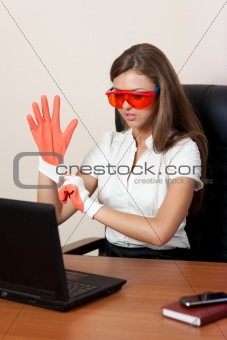 young woman behind a table with the laptop in gloves and orange 